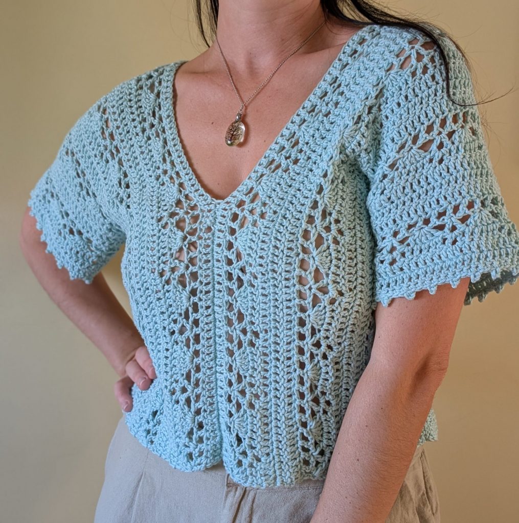crochet aqua lace top worn by a woman on a neutral background