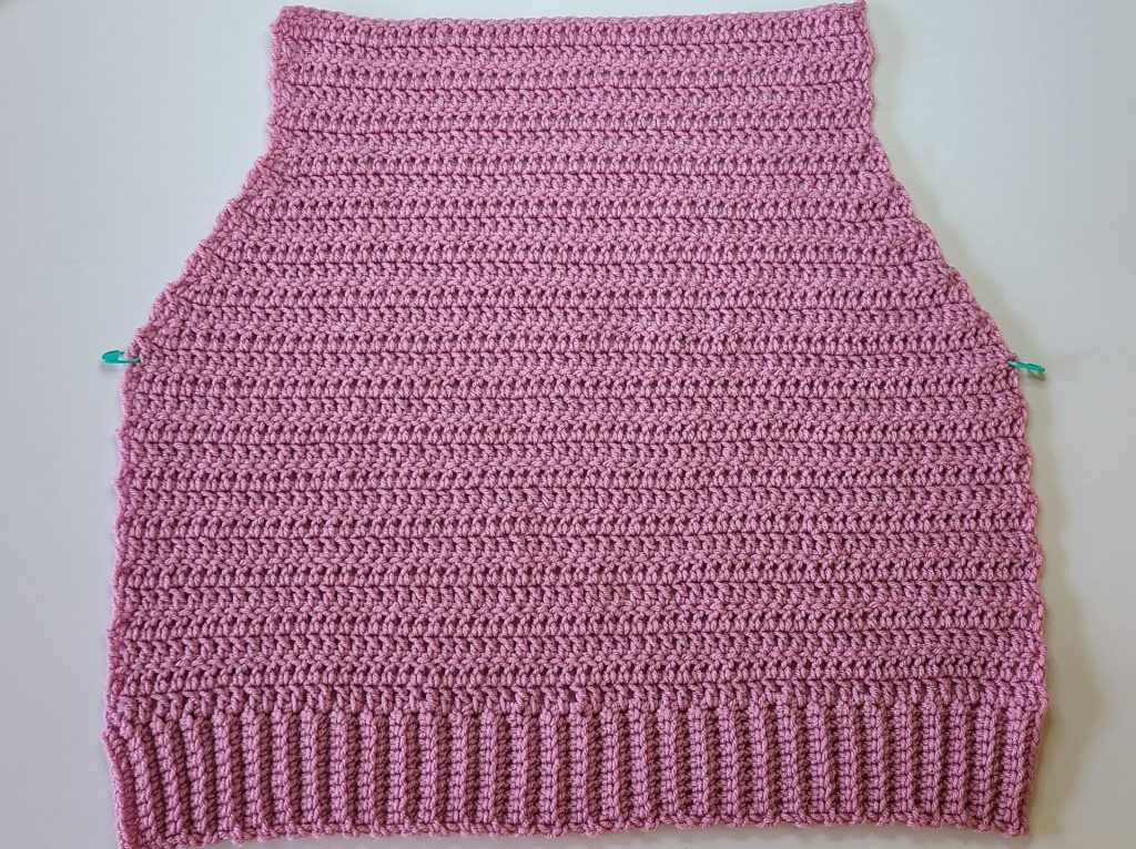 Crochet pink cozy vest back panel work in progress placed on white background
