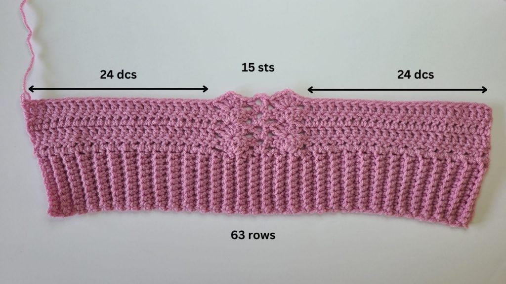 Work in progress of crochet pink cozy vest front panel photographed on bright white background.