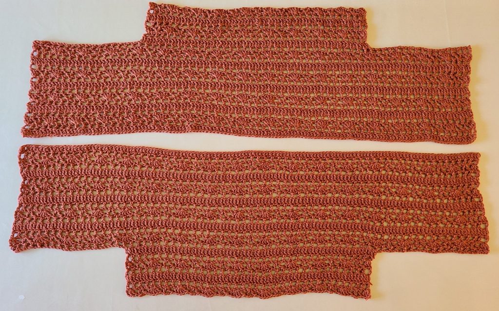 Two long rust-colored crochet lace panels laid flat, showing repeating openwork stitch rows.