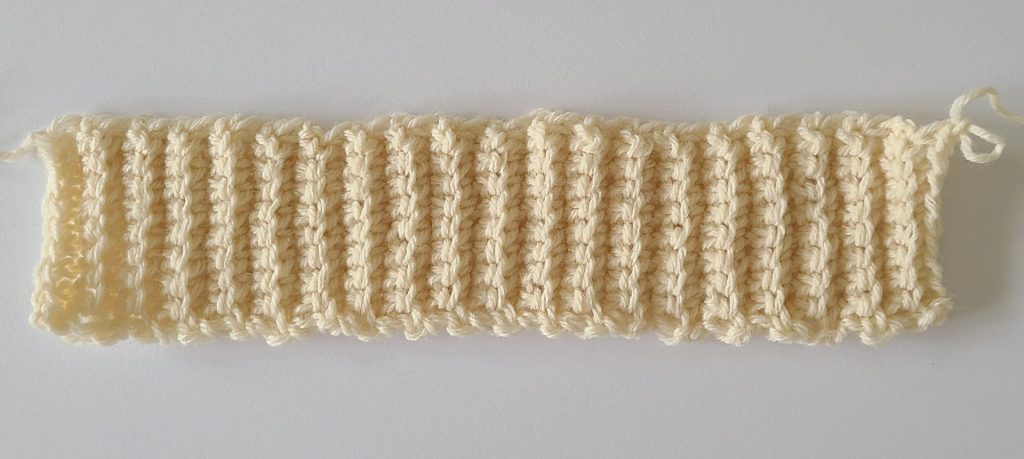 One beige ribbing crochet leg warmer displayed on a flat white background, showing texture and stitch details.
