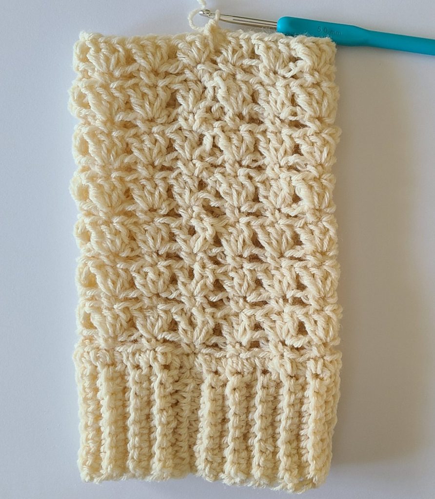 One beige crochet leg warmer displayed on a flat white background, showing texture and stitch details without top ribbing.