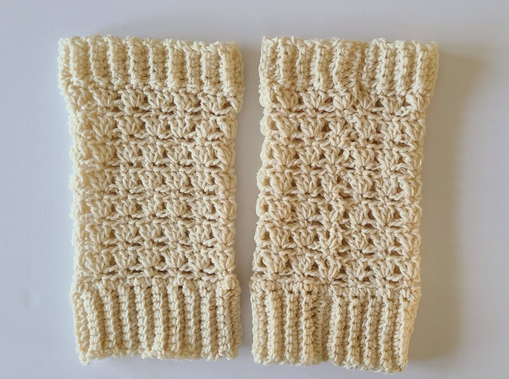 Beige crochet leg warmer displayed on a flat white background, showing texture and stitch details.