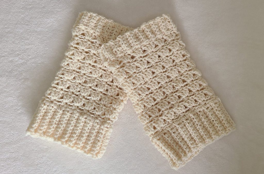 “Beige crochet leg warmer displayed on a flat white background, showing texture and stitch details.”