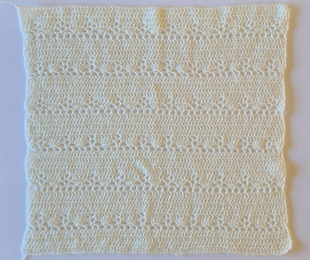 Flat crochet back panel of a lacy sweater worked in an open lace stitch pattern