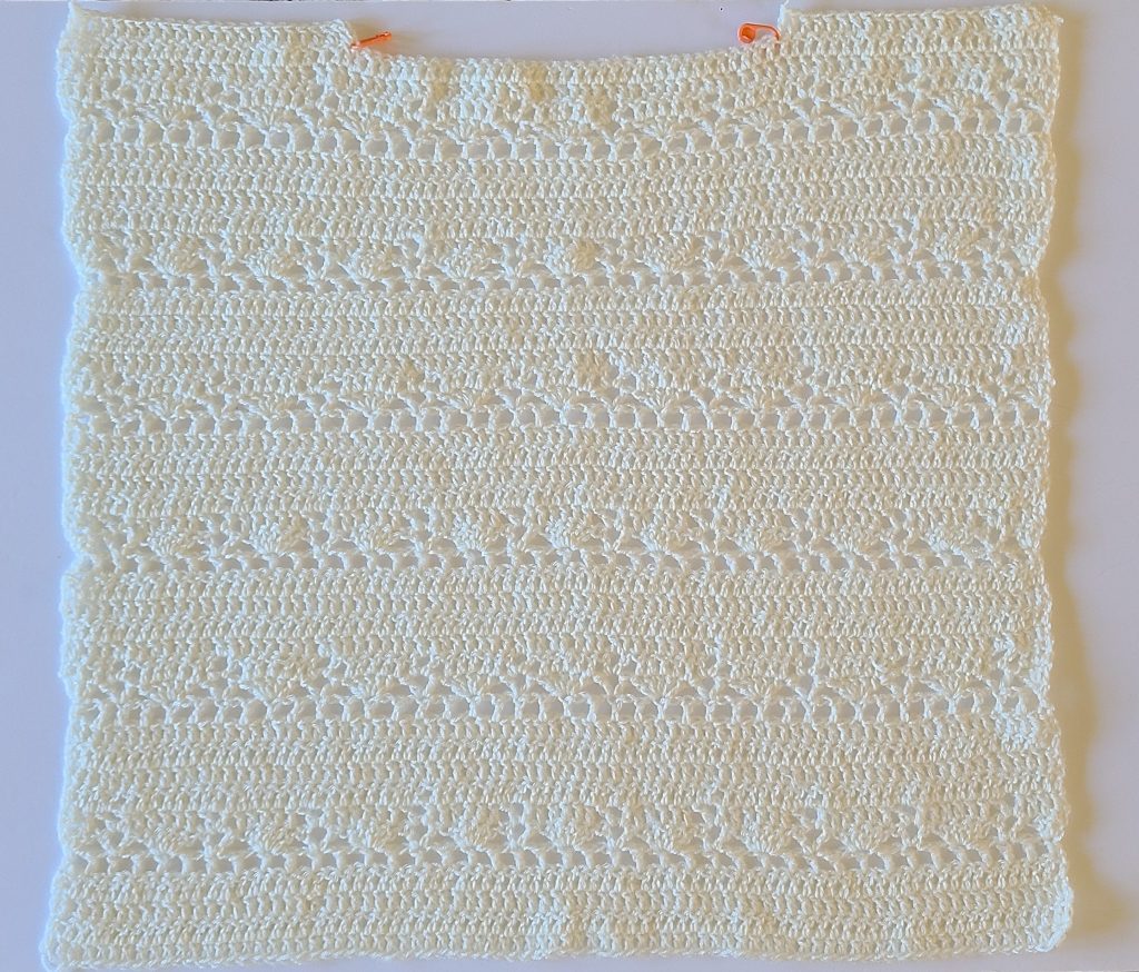 Flat crochet front panel of a lacy sweater worked in an open lace stitch pattern