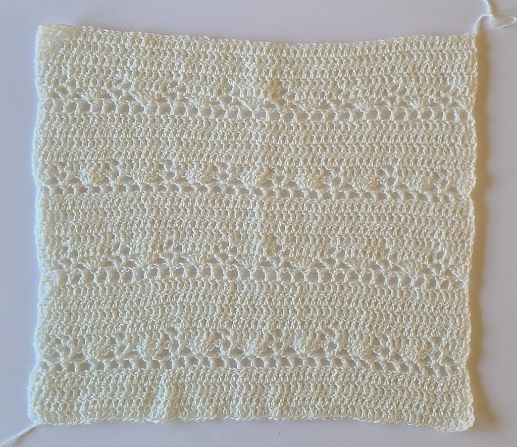 Flat crochet sleeve panel of a lacy sweater worked in an open lace stitch pattern