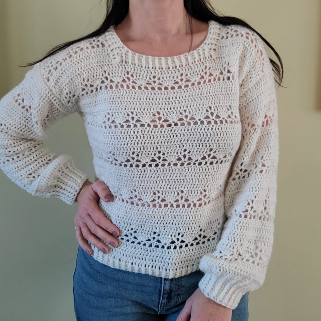 Woman wearing The Lora Crochet Lacy Sweater featuring a refined neck border in cream yarn