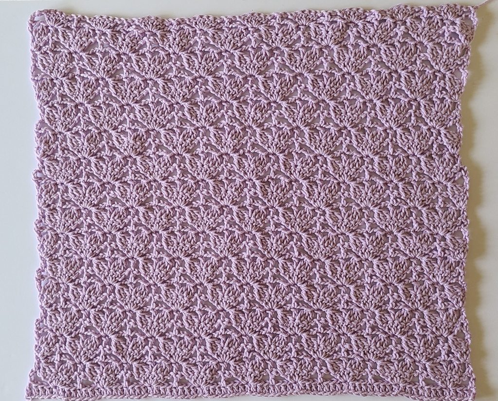 Back panel of lavender crochet lace sweater worked flat in textured shell stitch.