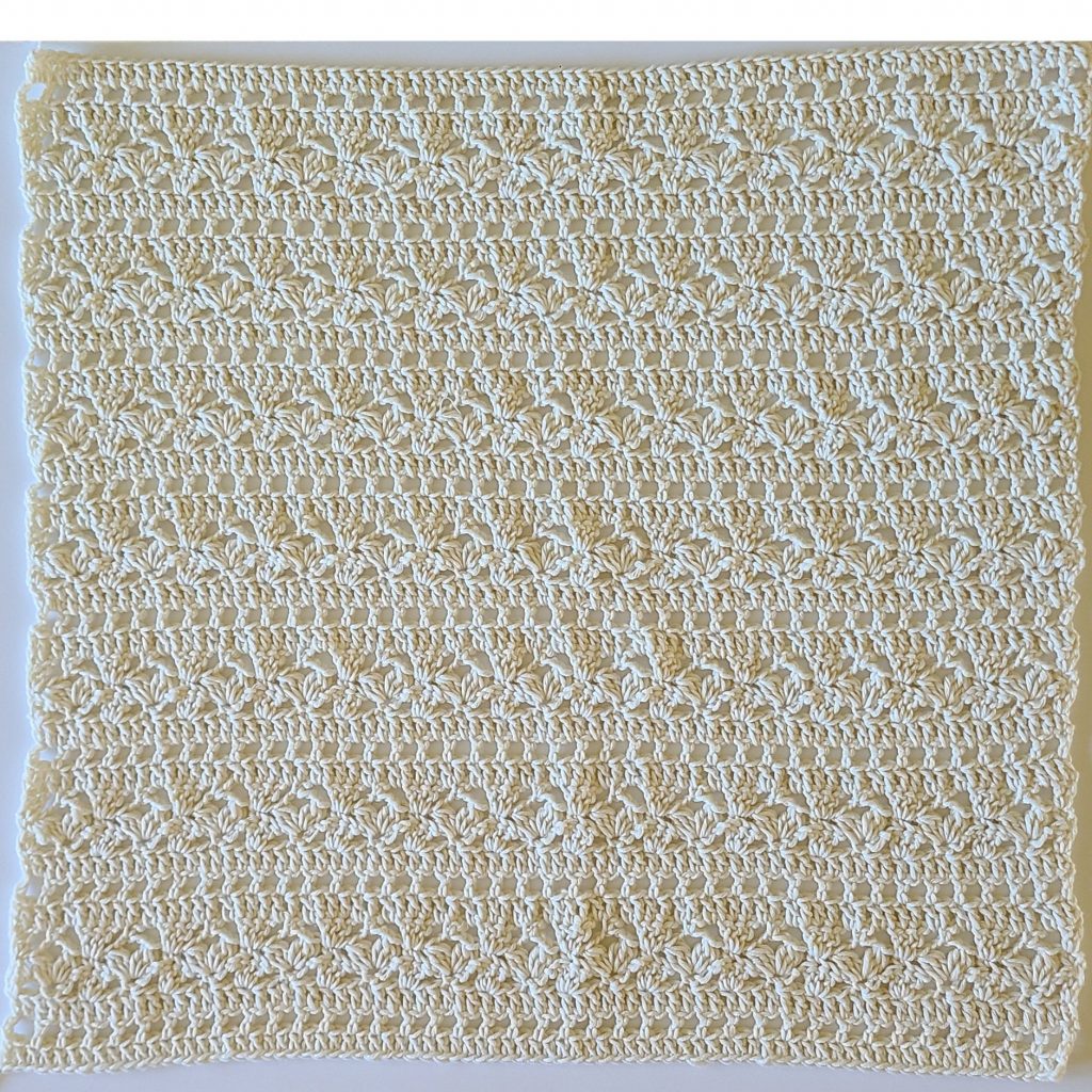 Back panel of a handmade summer lace crochet top laid flat showing detailed stitch pattern