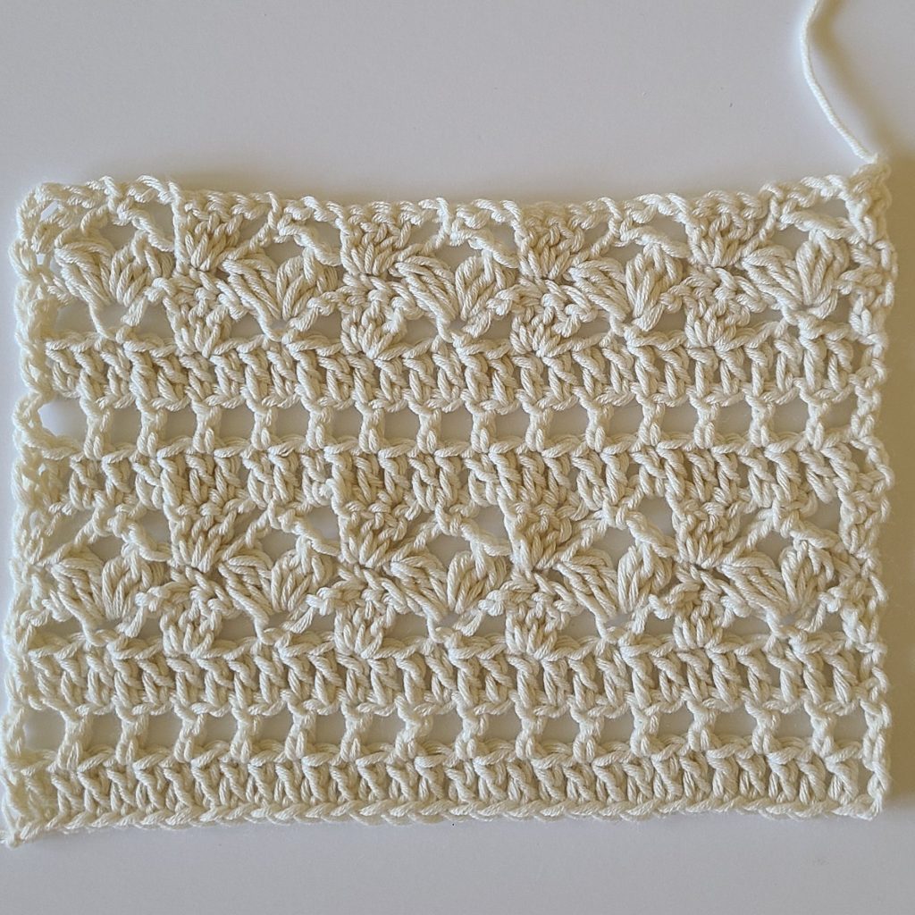Close-up crochet swatch showing a delicate lace stitch pattern used for a summer crochet top
