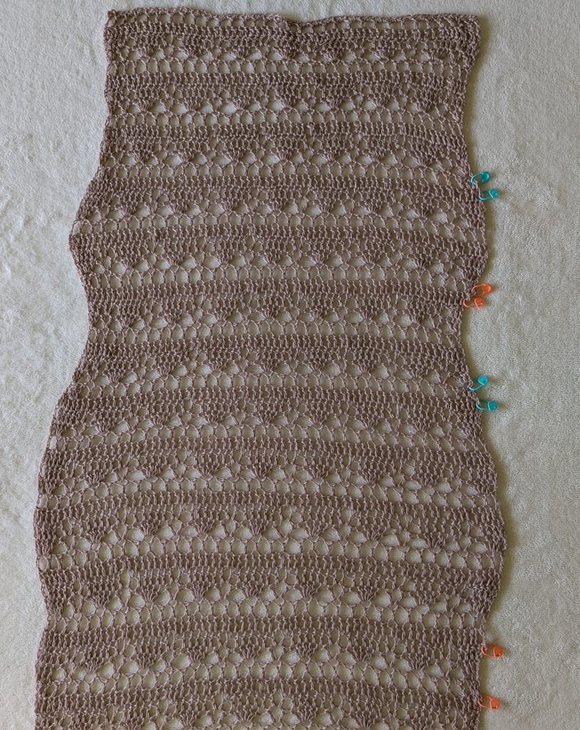 Crochet dress panel showing increase and decrease sections marked with stitch markers for waist and hip shaping.