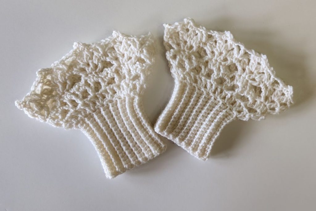 Finished crochet wrist lace cuffs laid flat to show the delicate lace stitches and scalloped edges.