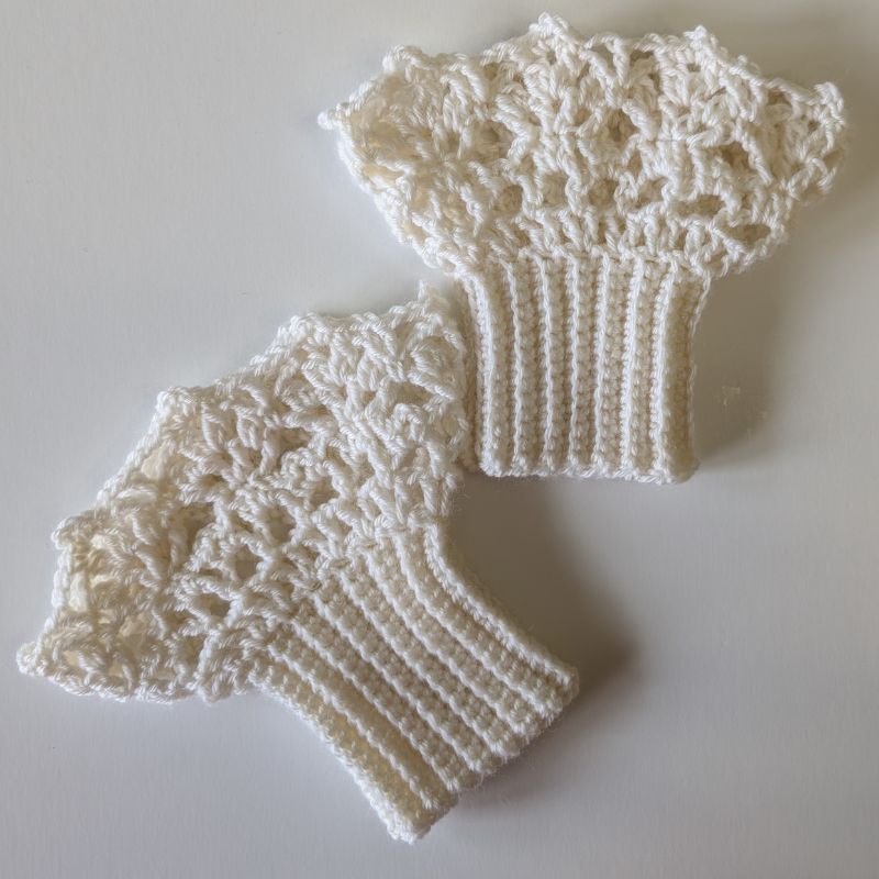 Finished crochet wrist lace cuffs laid flat to show the delicate lace stitches and scalloped edges.